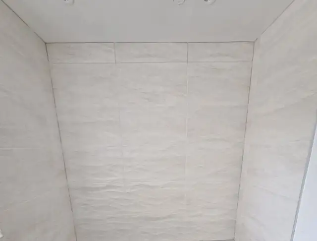 Textured white wall tiles around a new bath