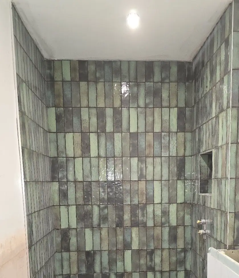 Green glazed brick-style tiles in a walk-in shower with a tiled niche, by CKP Tiling